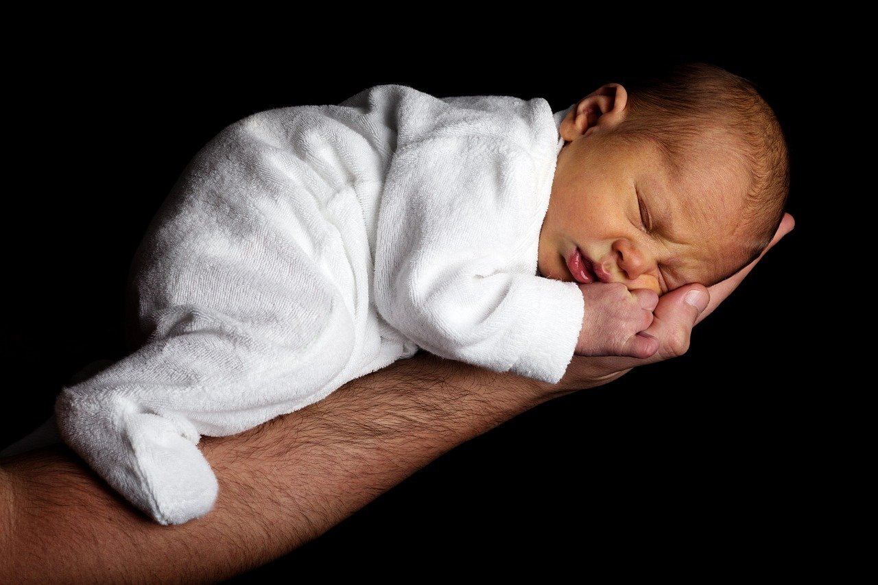 infant sleeping on man's arm